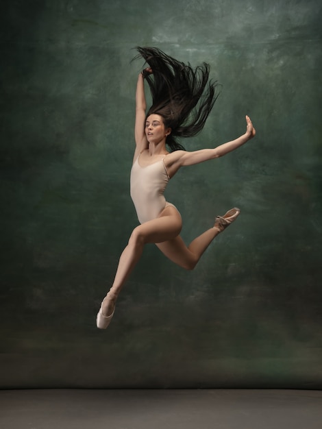 Giovane ballerina tenera graziosa sul fondo verde scuro dello studio