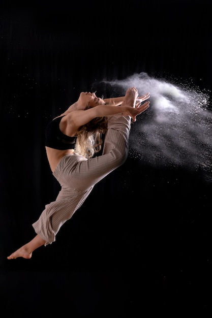 Giovane ballerino che esegue un salto nella sessione fotografica in studio con un balletto su sfondo nero