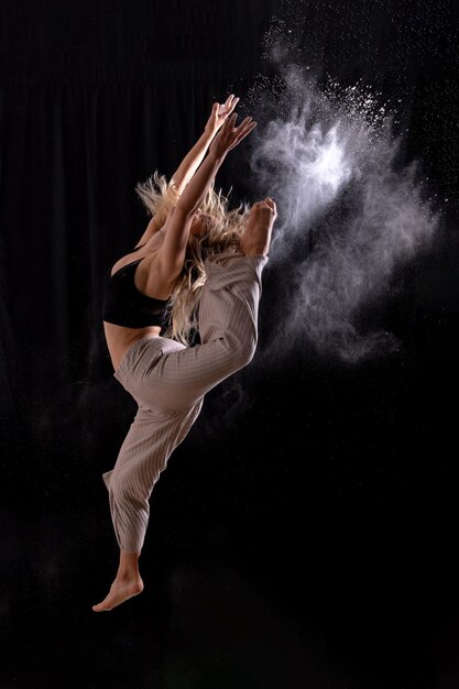 Giovane ballerino che esegue un salto nella sessione fotografica in studio con un balletto su sfondo nero