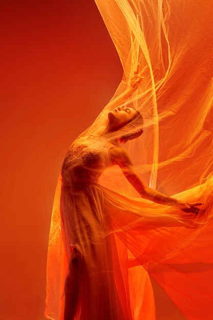Giovane ballerino femminile grazioso o ballerina classica che balla allo studio rosso. Modello caucasico su scarpe da punta