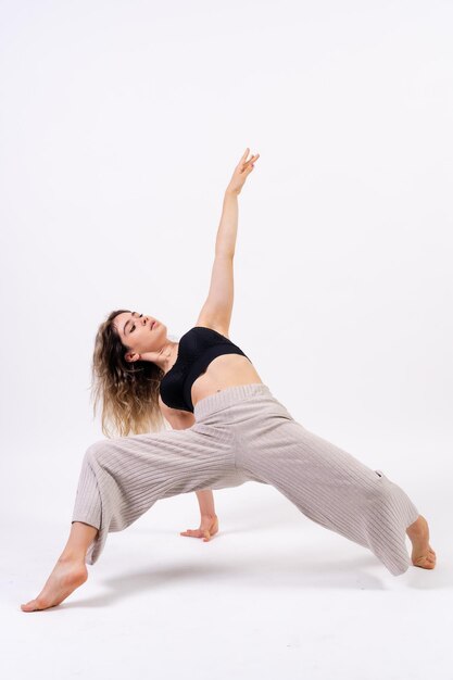 Giovane ballerino in sessione fotografica in studio con un balletto su sfondo bianco che esegue esercizi sul pavimento