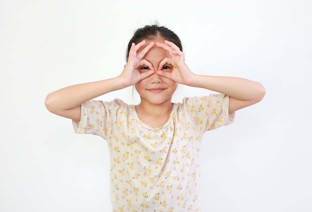 Giovane bambina asiatica che guarda attraverso il binocolo immaginario isolato