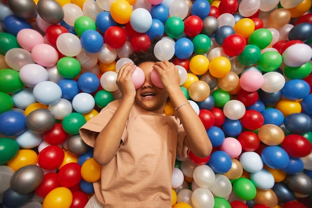 giovane bambina divertirsi con le palle in piscina nel parco di divertimenti