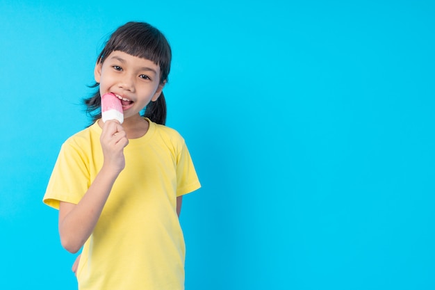 Giovane bambino asiatico della ragazza che mangia il gelato e pubblicazione divertente