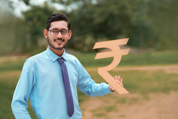Giovane banchiere o finanziere indiano che tiene in mano il simbolo delle rupie