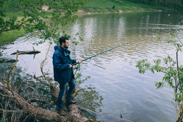 Giovane barbuto che pesca sul lago