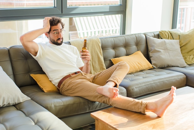 Giovane barbuto uomo freddo seduto su un divano a casa
