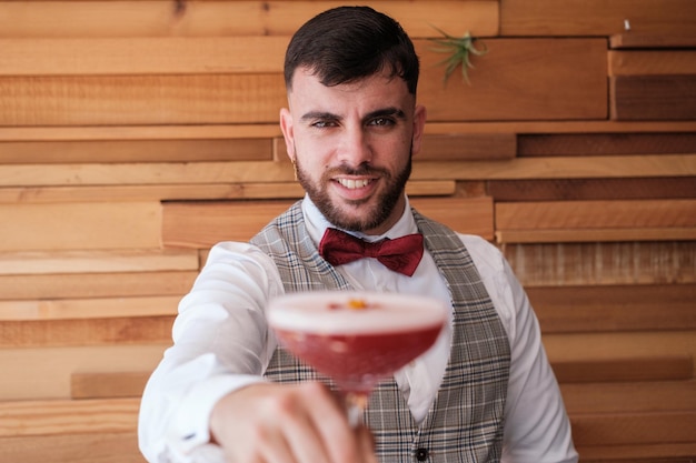 Giovane barista che offre un cocktail colorato ai suoi clienti Concetto barista beve la vita notturna