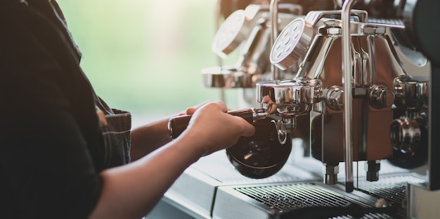 Giovane barista femminile professionista che produce caffè con la macchina per il caffè