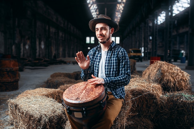 Giovane batterista maschio contro tamburo di legno africano