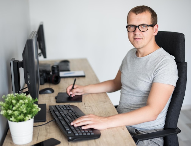 Giovane bel fotografo maschio che modifica le immagini con il computer in un ufficio moderno oa casa