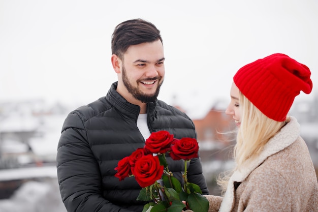 Giovane bel ragazzo che dà a una ragazza un mazzo di rose il giorno di San Valentino