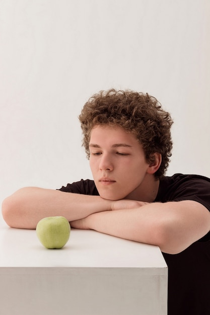 Giovane bel ragazzo che guarda una mela verde