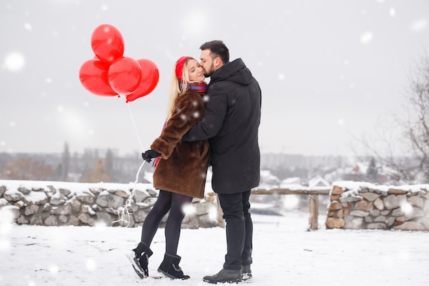 Giovane bel ragazzo e donna con palloncini che camminano il giorno di San Valentino