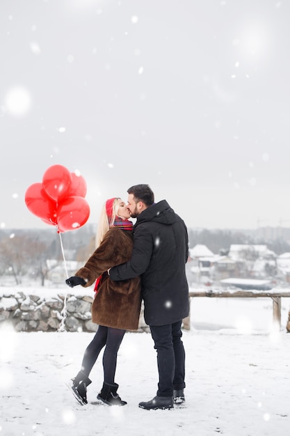 Giovane bel ragazzo e donna con palloncini che camminano il giorno di San Valentino