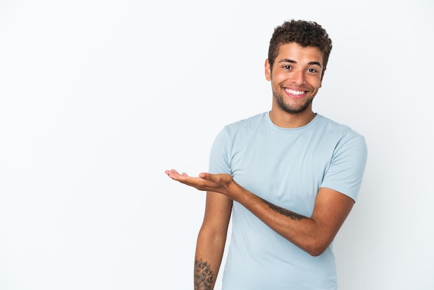 Giovane bell'uomo brasiliano isolato su sfondo bianco che presenta un'idea mentre guarda sorridendo verso