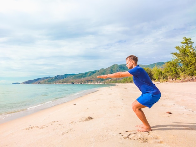 Giovane bell'uomo che fa sport eseguendo esercizi di allenamento vicino al mare al mattino durante la quarantena Vita attiva senza protezione chirurgica della maschera facciale sterilizzante