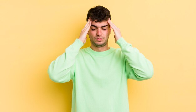 Giovane bell'uomo che guarda concentrato pensieroso e ispirato brainstorming e immaginando con le mani sulla fronte