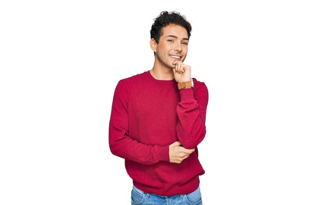 Giovane bell'uomo che indossa abiti casual che guarda fiducioso alla telecamera sorridendo con le braccia incrociate e la mano alzata sul mento. pensare positivo.