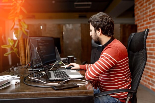 Giovane bell'uomo che lavora in ufficio al computer. Uomo in panno casual che lavora in ufficio.