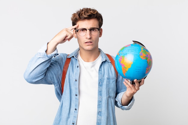 Giovane bell'uomo che si sente confuso e perplesso, mostrando che sei pazzo. studente con in mano una mappa del globo