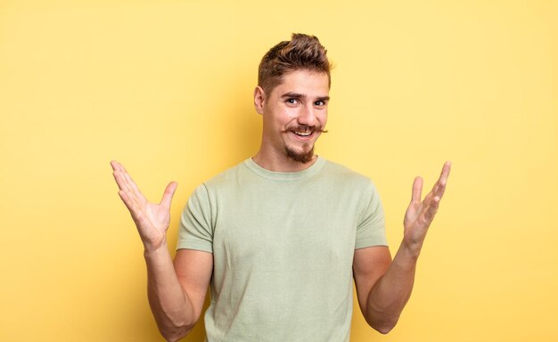 Giovane bell'uomo che si sente felice, eccitato, sorpreso o scioccato, sorridente e stupito per qualcosa di incredibile. strano concetto di baffi