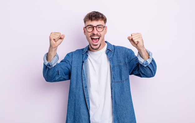 Giovane bell'uomo che si sente felice, sorpreso e orgoglioso, grida e celebra il successo con un grande sorriso