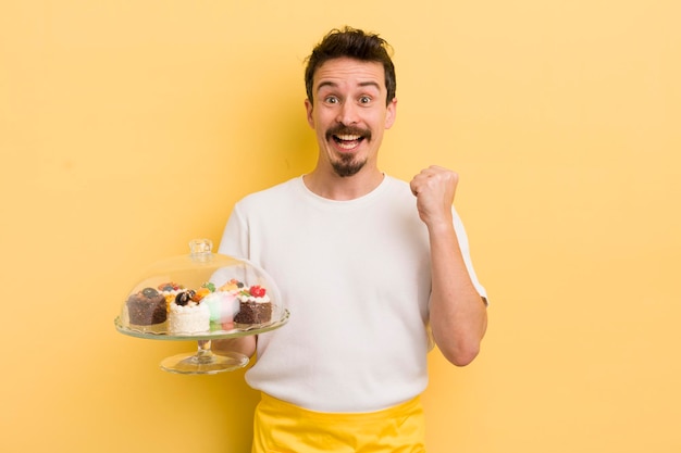 Giovane bell'uomo che si sente scioccato e ride e celebra il concetto di torte fatte in casa di successo