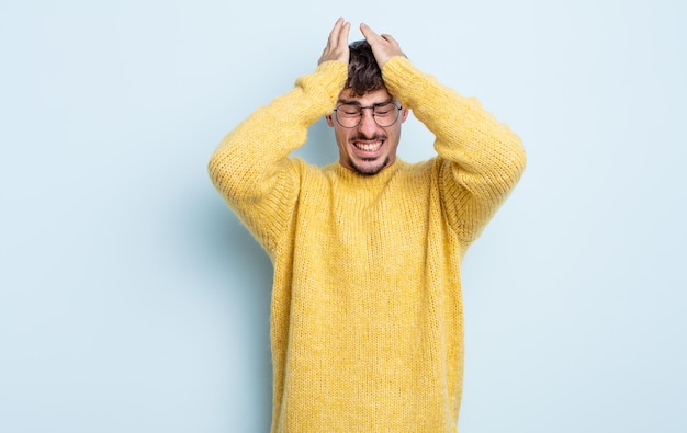 Giovane bell'uomo che si sente stressato e ansioso, depresso e frustrato per il mal di testa, alzando entrambe le mani alla testa