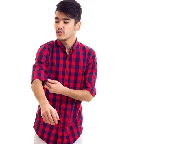 Giovane bell'uomo con i capelli scuri che indossa una camicia a quadri rossa su fondo nero bianco in studio