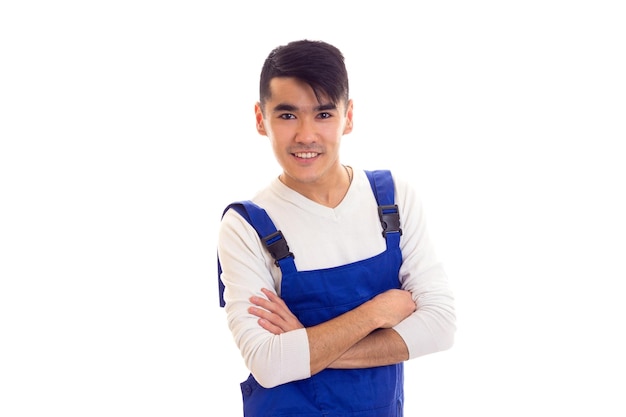 Giovane bell'uomo con i capelli scuri che indossa una camicia bianca e tuta blu su sfondo bianco in studio