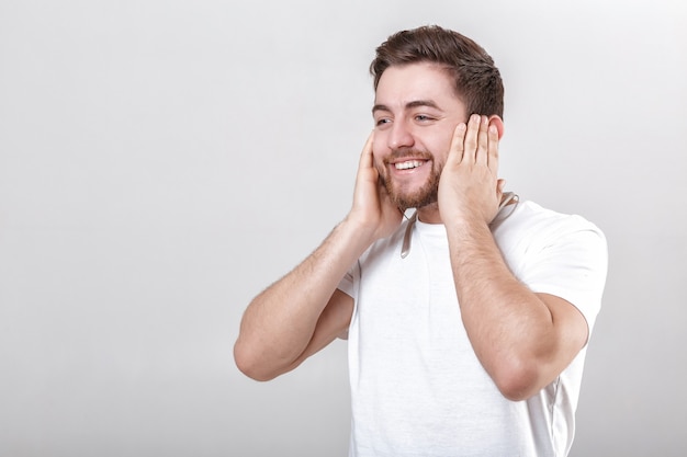 Giovane bell'uomo con la barba in maglietta che ascolta musica in cuffia