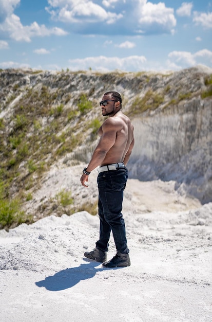 Giovane bell'uomo in forma che si diverte sulla spiaggia Forte giovane modello maschile senza maglietta che tiene la camicia