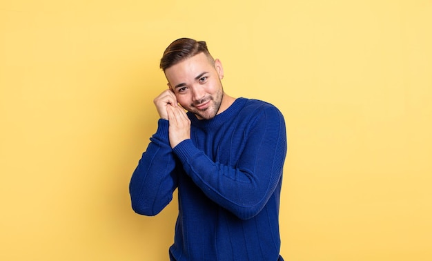 Giovane bell'uomo innamorato e dall'aspetto carino, adorabile e felice, sorridente romanticamente con le mani accanto al viso