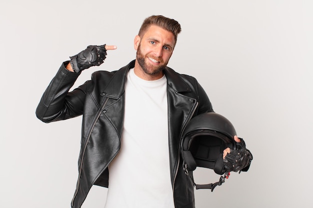 Giovane bell'uomo sorridente che punta con sicurezza al proprio concetto di casco da moto ampio sorriso