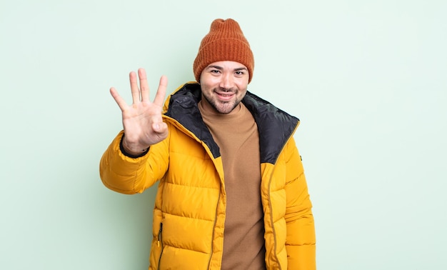 Giovane bell'uomo sorridente e dall'aspetto amichevole che mostra il concetto di tempo freddo numero quattro