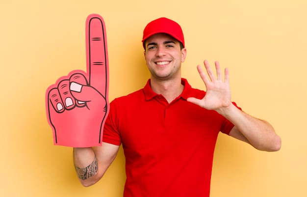 Giovane bell'uomo sorridente felicemente agitando la mano dandoti il benvenuto e salutandoti il concetto di mano numero uno