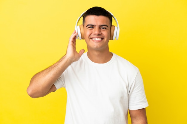 Giovane bell'uomo su sfondo giallo isolato ascoltando musica