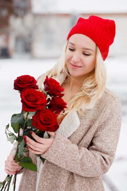 Giovane bella bionda con bouquet di rose rosse il giorno di San Valentino