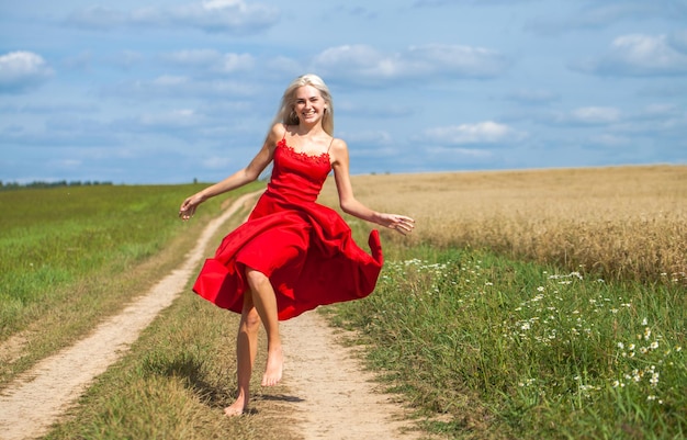 giovane bella bionda in un vestito rosso che posa in un campo di grano