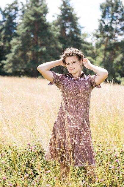 Giovane bella bruna con la treccia in testa in un abito in stile country sul campo