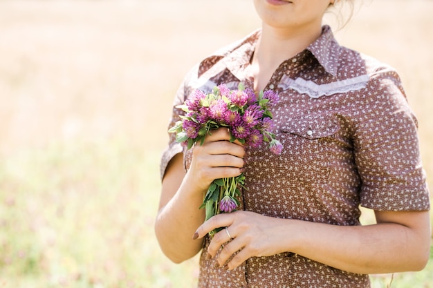 Giovane bella bruna con la treccia in testa in un abito in stile country sul campo