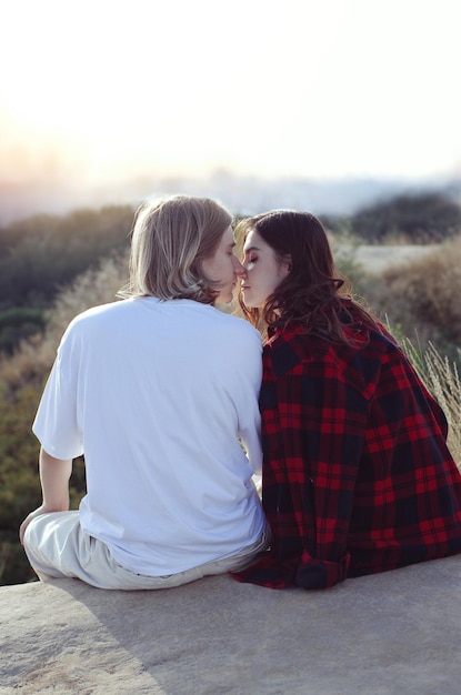 Giovane bella coppia adolescente storia d'amore ragazzo e ragazza seduta a guardare la vista del tramonto dal retro