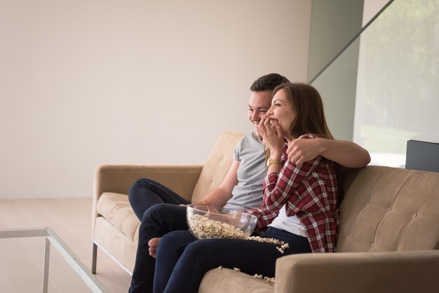 giovane bella coppia che si gode il tempo libero guardando la televisione con popcorn nella loro lussuosa villa di casa