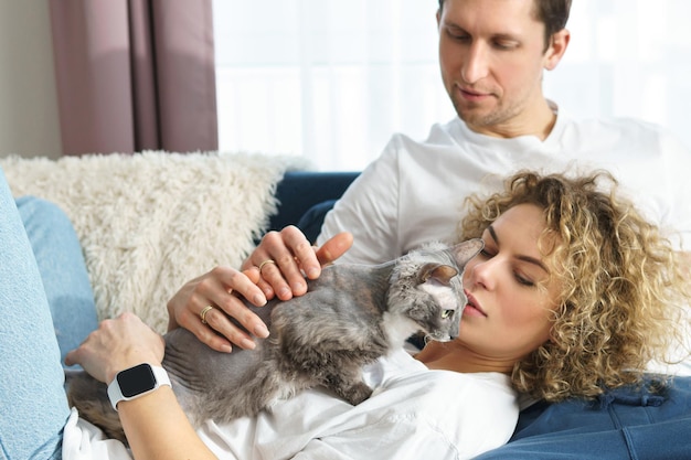 Giovane bella coppia con il loro adorabile gatto che si rilassa a casa