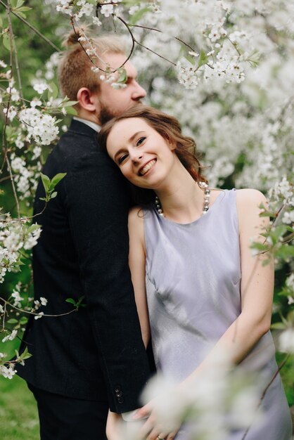 Giovane bella coppia in giardino sullo sfondo dei fiori di ciliegio 1