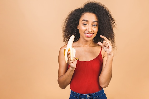 Giovane bella donna afro-americana che mangia banana