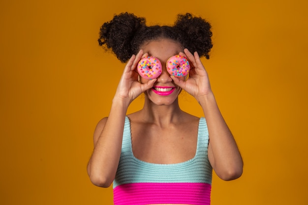 Giovane bella donna afro con una ciambella