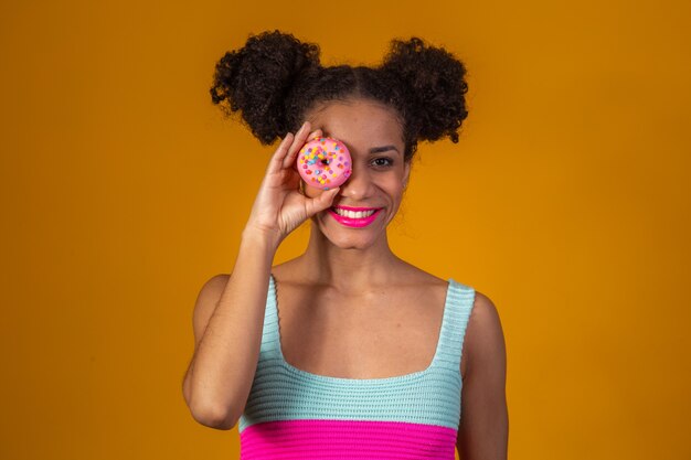 Giovane bella donna afro con una ciambella