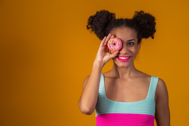 Giovane bella donna afro con una ciambella